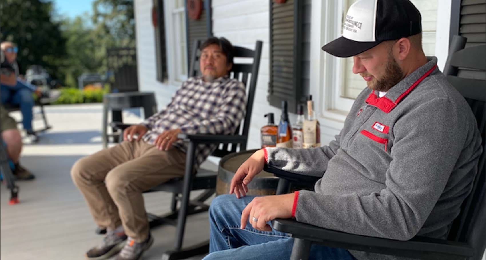 Chef Edward Lee and Freddie Noe Jr., 8th generation family distiller at Jim Beam, sitting on a porch with bourbon on barrel